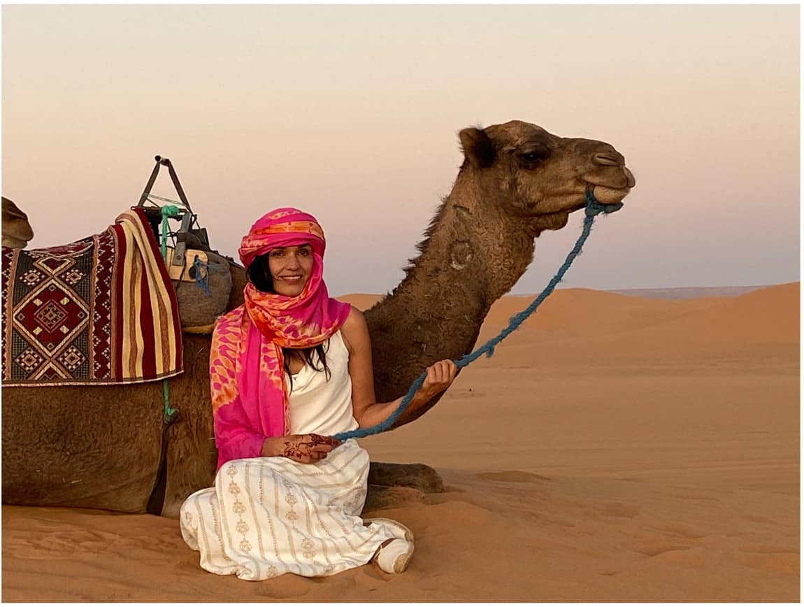 Girl sitting next to a camel